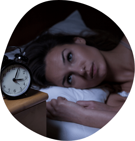 Woman awake in bed staring at alarm clock