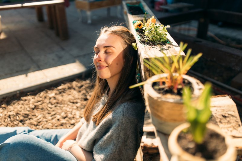 A woman closing her eyes and enjoying the sunshine in her garden